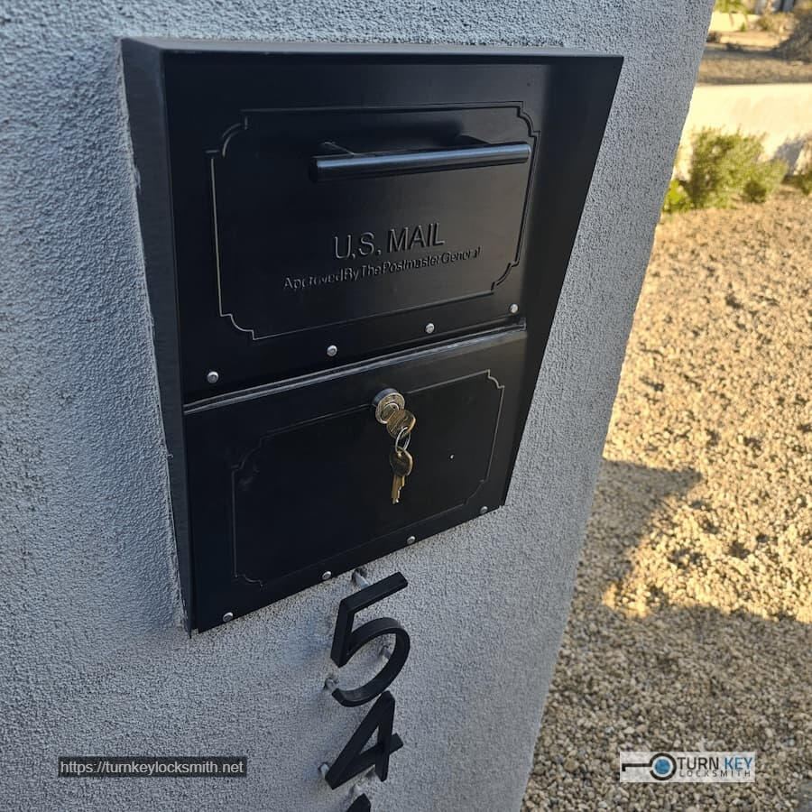 Black residential USPS-approved wall-mounted mailbox with newly installed replacement lock and keys by mobile locksmith service in Arcadia neighborhood in Phoenix, Arizona
