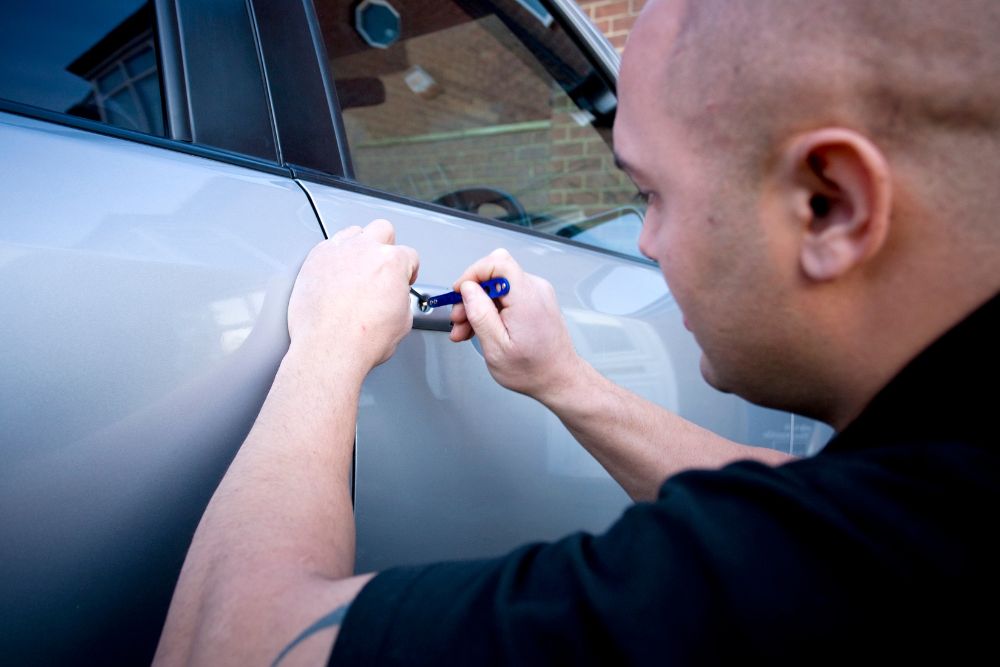 Man using a tool to break into a car door. Automotive security concern. Turn Key Locksmith, Phoenix AZ