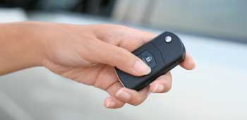 Hand holding a black car key fob with lock and unlock buttons. Turn Key Locksmith, Phoenix AZ